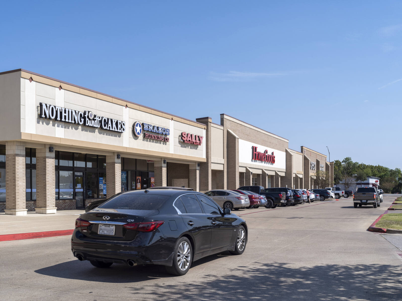 Black car passes Nothing Bundt Cakes and drives towards HomeGoods.