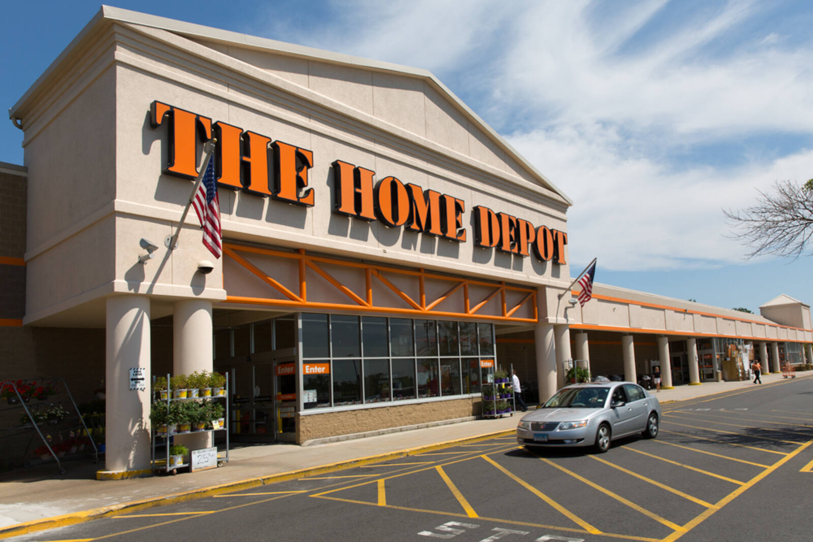 Silver car in front of The Home Depot with plants set out on the left.