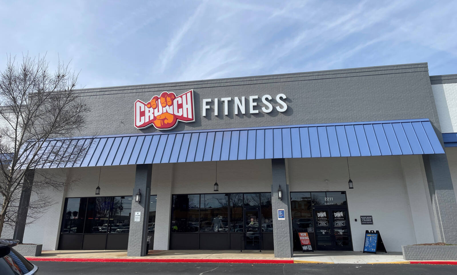Trees and blue sky over Crunch Fitness at shopping center.