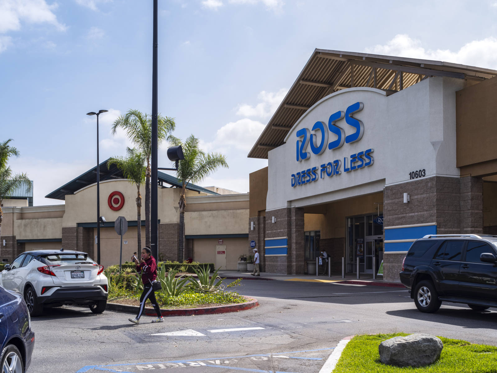 Ross Dress for Less with pedestrian crossing into parking lot with palm trees.