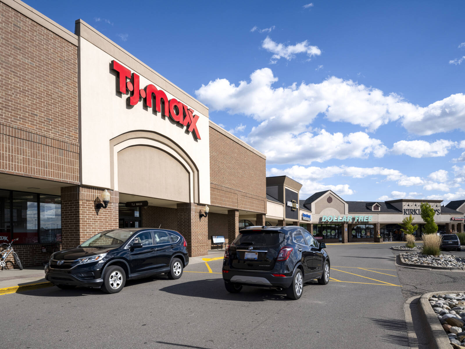 Two cars in crosswalk of TJ Maxx at a shopping center.
