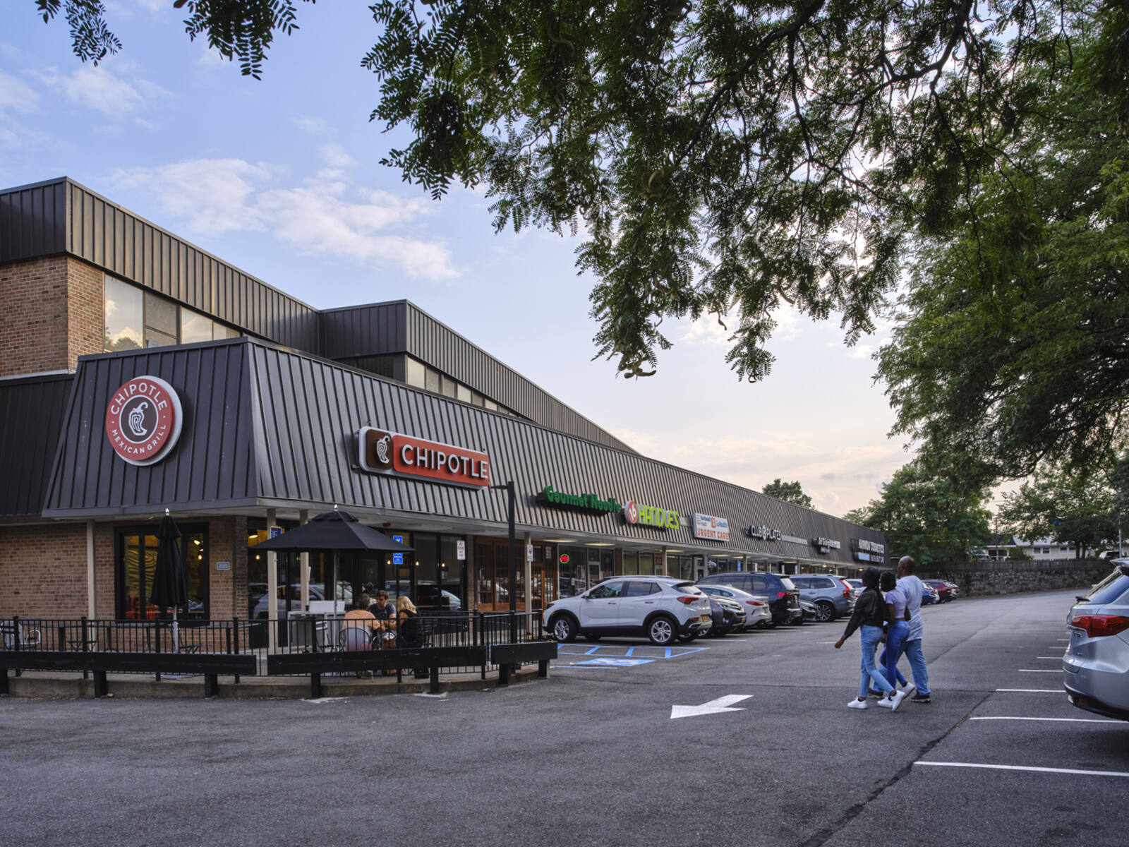 Chipotle with outdoor seating and pedestrians crossing parking lot.