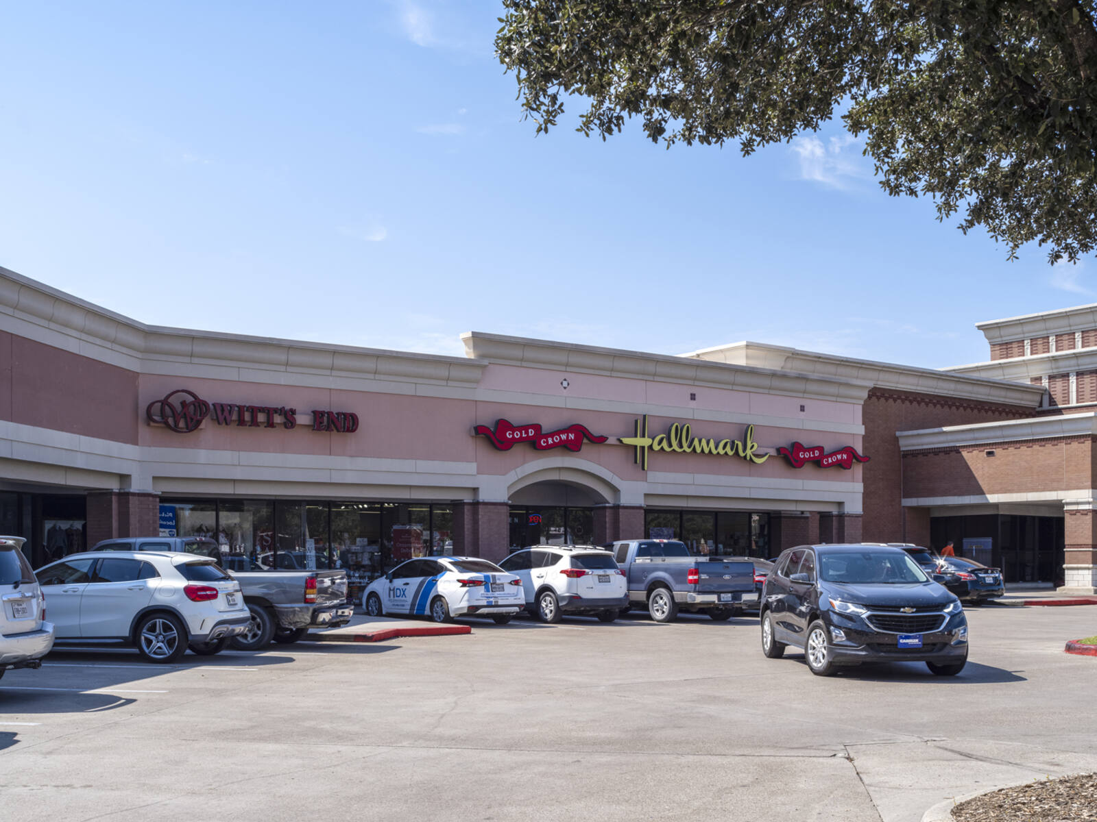 SUV pulls out of busy parking lot in front of Hallmark gift shop.
