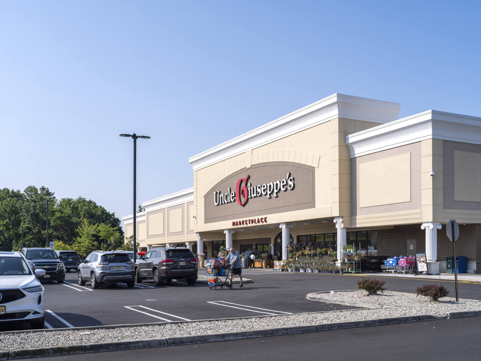 Customer pushing a cart through parking lot of Uncle Giuseppe's supermarket.