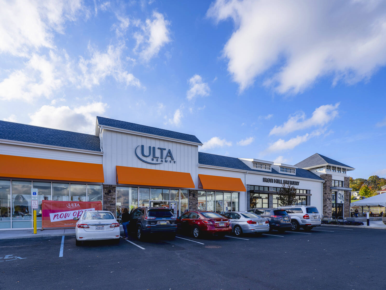 Cars parked, lined along entrance to Ulta Beauty and clouds and blue sky